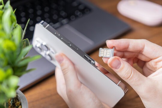 Human hands inserting a dual SIM card into a sleek white smartphone, representing essential mobile technology, global connectivity, and network activation service