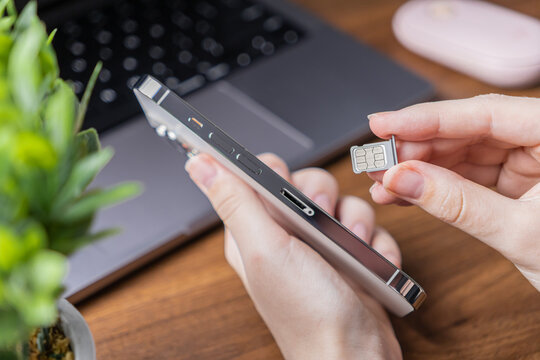 Close-up of human hands holding a contemporary smartphone, preparing to insert a SIM card tray for mobile network connectivity and device setup