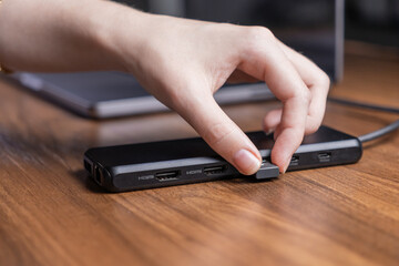 Person's hand plugs a USB flash drive into a versatile black docking station, enhancing laptop connectivity for an efficient digital workspace