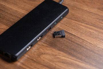 Black USB hub with multiple ports, positioned beside a tiny wireless dongle, essential for expanding modern digital workspace connectivity and device peripherals