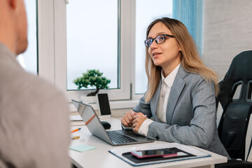 employees communicate in the office. Beautiful young blonde girl speaking with a male on job interview in the large bright office.