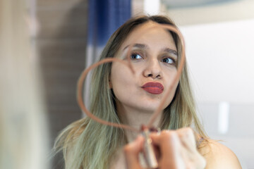 concept of loving yourself, self-love. A young beautiful woman draws a heart with lipstick on the...