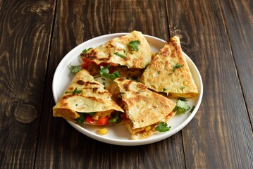 Chicken quesadilla with fresh vegetables on wooden table