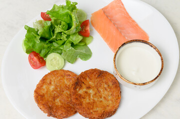Two golden potato pancakes with salmon salad and sour cream