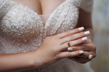 Hands adorned with rings showcase elegance in a bridal gown during a moment of preparation