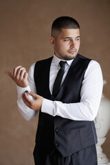 Man adjusting cufflinks while preparing for a formal event in elegant attire