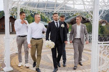 Groomsmen supporting the groom during a wedding ceremony in a scenic outdoor venue