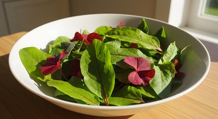 Fresh Green Salad with Red Leaves in a White Bowl on a Wooden Table