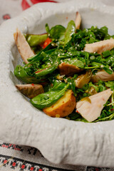 Fresh salad with chicken, greens and vegetables in a white plate