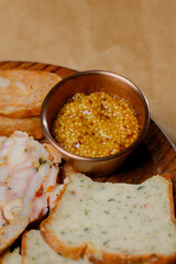 Meat appetizer with bread, onions and two sauces on a wooden board.