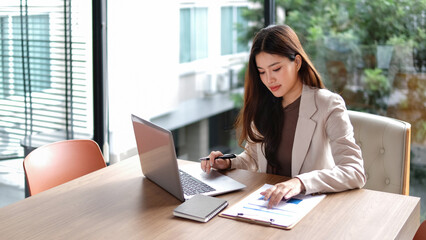 Businesswoman sitting working with laptop on desk in office