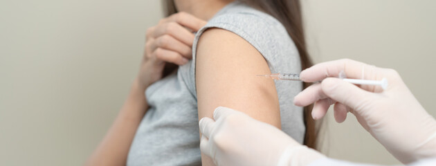 People getting a vaccination to prevent pandemic concept. Woman in medical face mask  receiving a dose of immunization coronavirus vaccine from a nurse at the medical center hospital