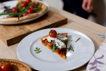 Indulge in a Delicious Slice of Gourmet Pizza Topped with Sweet Cherry Tomatoes and Fresh Arugula