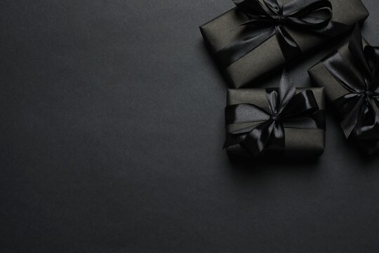 Black Friday. Top view of black gift boxes tied with ribbons,  on a dark backdrop, providing space for your message or promotion