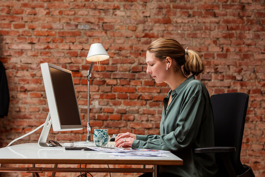 Female small business owner working at her desk in a loft type office space.