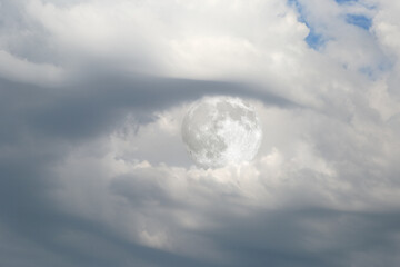 The full moon is hidden behind storm clouds in the shape of a human eye. The scene is created using photomontage and evokes mystery and a fantastical atmospheric mood.