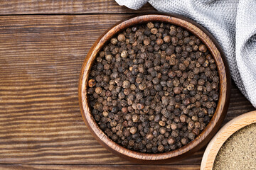Black peppercorns and ground black pepper powder on wooden background	