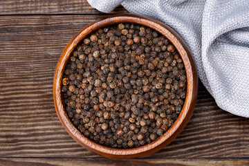 Black peppercorns on wooden background	