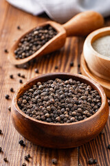 Black peppercorns and ground black pepper powder on wooden background