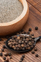 Black peppercorns and ground black pepper powder on wooden background	