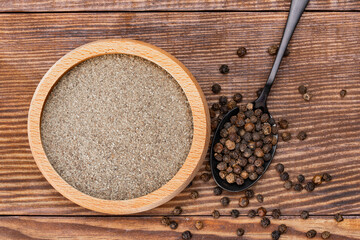 Black peppercorns and ground black pepper powder on wooden background	