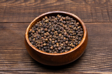 Black peppercorns on wooden background	