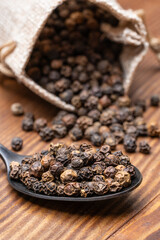 Black peppercorns on wooden background	