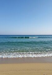 Fototapeta premium Gentle ocean waves meet the soft sandy shore under a clear sky, perfect for a tranquil escape and natural beauty ,vacation ,sand ,coast