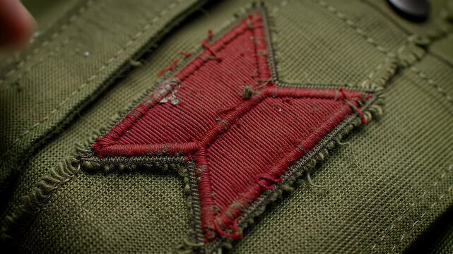 Macro Detail of Red Embroidered Patch on Olive Green Textured Fabric