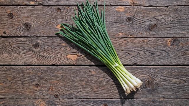 Top-down view of fresh green onions on rustic wooden planks. Perfect for a cooking video, showcasing natural textures and vibrant colors.