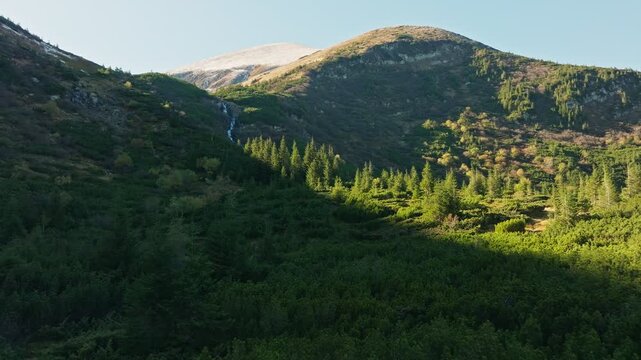 Experience a majestic mountain landscape with a stunning waterfall