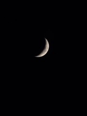 A peaceful crescent moon glowing softly against the dark night sky. © soony