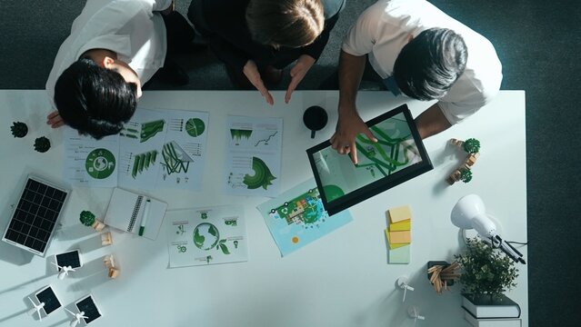 Top view of manager hold tablet display clean energy investment at meeting. Aerial view of skilled business team working together and planning to use sustainability environmental energy. Alimentation.