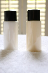 Travel size toiletries standing on a white towel, providing hotel amenities for hygiene, beauty and self care