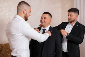 Groom gets ready with friends before wedding ceremony in bright indoor setting