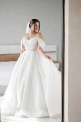 Bride wearing a beautiful white wedding dress in a bright bedroom setting