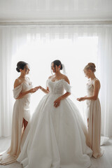 Fototapeta premium Friends assist the bride in getting ready for her wedding day in soft natural light