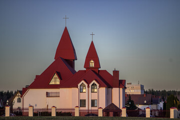 Architectural structure featuring a unique design with red roofs and spires, surrounded by a fence...
