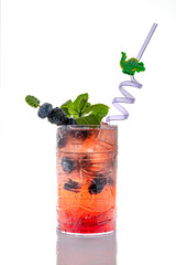 Blackberry cocktail with mint and ice on white background. Vibrant blackberry cocktail with ice, mint leaves, and decorative purple straw in clear tiki glass.