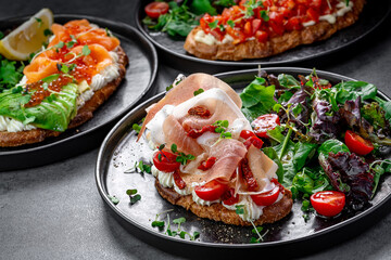 Bruschetta with salmon, avocado, and red caviar. Bruschetta topped with salmon slices, avocado, red caviar, and cream cheese served with salad and lemon.
