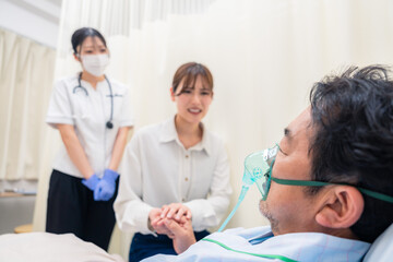 Obraz premium 人工呼吸器をつけた家族のお見舞いをする若い女性