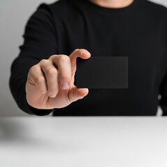 Person holding a black card in hand, close-up shot, business concept.