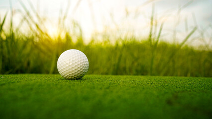 Golf clubs and balls on a green lawn in a beautiful golf course with morning sunshine.