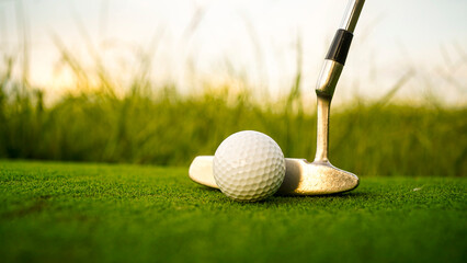 Golf clubs and balls on a green lawn in a beautiful golf course with morning sunshine.