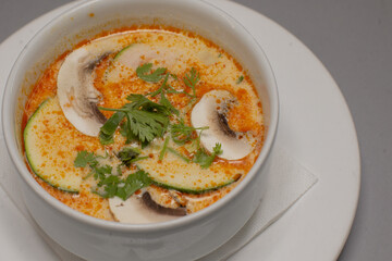 A delightful dish of creamy soup, generously topped with mushrooms and fresh herbs, served elegantly in a white bowl