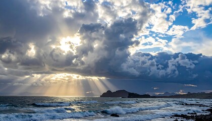 A dramatic scene of sunbeams piercing through dark storm clouds over a restless ocean and a distant, rocky coastline