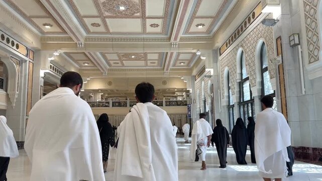 Muslim pilgrims in Ihram clothing walking through the long corridor while performing the Sa'i ritual between the hills of Safa and Marwa. 