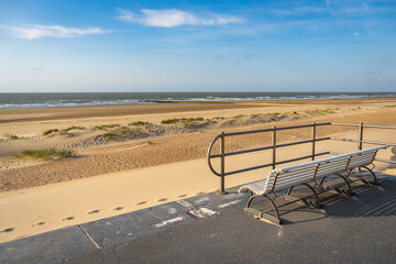 Park bench on the shore of North Sea. Wind makes structures in the sand at the ocean, natural art on the sandy beach, place to recreation on holiday