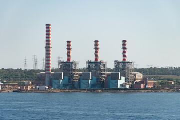 Coal-fired power plant with tall smokestacks in the port of Civitavecchia, Italy.