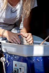 Close-up of hands shaping wet clay on electric pottery wheel
